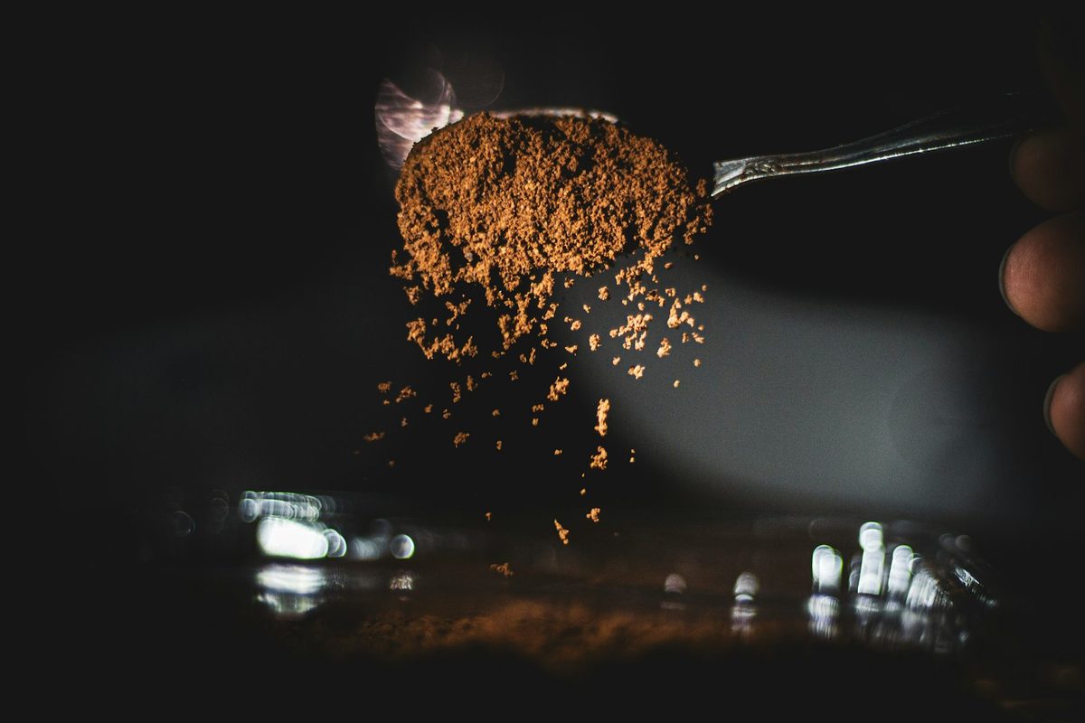Thìa bột cacao rơi xuống nền tối
