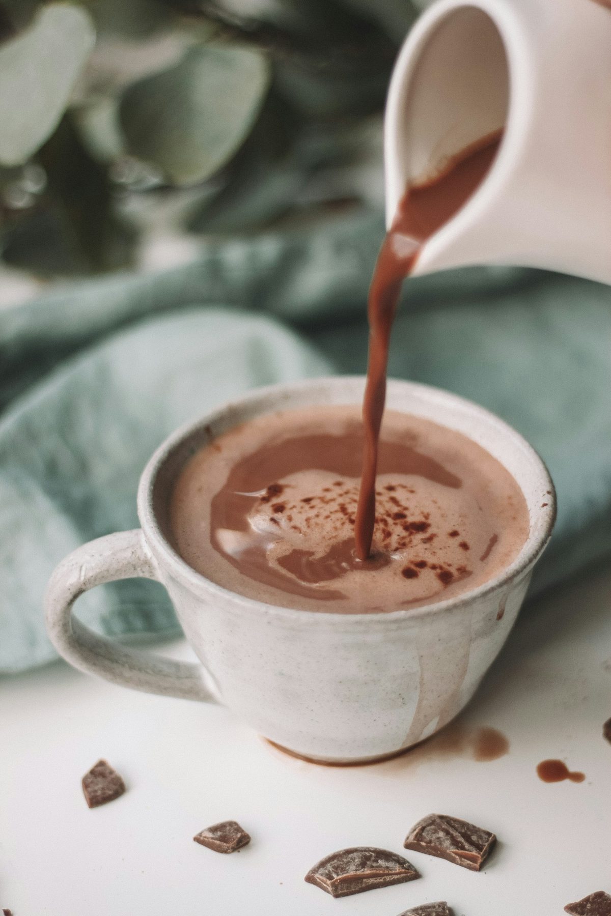 Rót cacao nóng vào tách sứ trắng